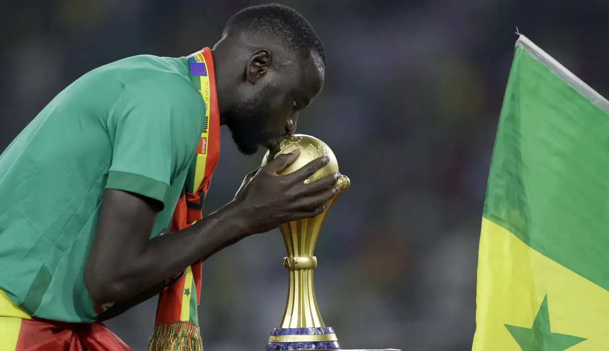 Gelandang Senegal Cheikhou Kouyate mencium trofi setelah memenangkan pertandingan final Piala Afrika 2022 atas Mesir di Paul Biya Stadium, Kamerun, Senin (7/2/2022) dini hari WIB. Sadio Mane membawa Senegal mengalahkan Mesir lewat adu penalti dengan skor 4-2. (AP Photo/Sunday Alamba)