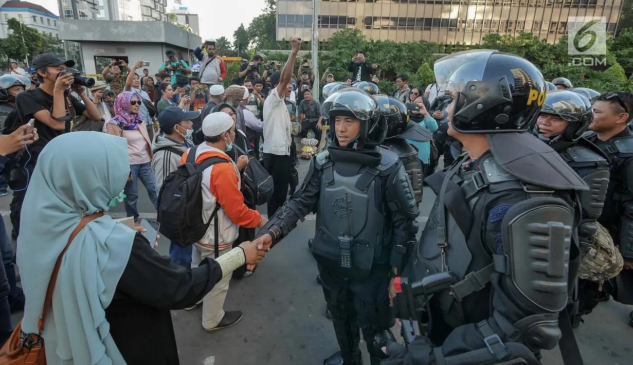 Sejumlah peserta aksi bersalaman dengan Polisi dari kesatuan Brimob saat gelar doa bersama di depan kantor Bawaslu, Jakarta, Jumat (24/5/2019). Mereka datang untuk mendoakan para demonstran yang meninggal saat aksi 21-22 Mei, pasca hasil penghitungan suara Pemilu 2019. (Liputan6.com/Herman Zakharia)