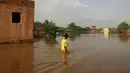 Seorang bocah lelaki Sudan mengarungi jalan yang banjir di daerah alqamayir di kota kembar ibu kota Omdurman (26/8/2020). (AFP Photo/Ashraf Shazly)