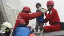 Petugas penyelamat mengevakuasi seorang anak yang selamat akibat gempa di Tainan, Taiwan Selatan (6/2). Gempa terjadi pukul 4 subuh tadi telah menghancurkan beberapa apartemen di kawasan Wei Guan, Tainan, Taiwan. (REUTERS/Stringer)