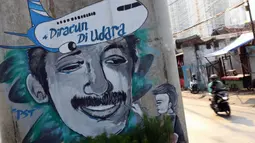 Pengendara melintas di sisi mural bergambar aktivis HAM, Munir di Jalan Ciledug Raya, Jakarta, Senin (7/9/2020). 7 September, 16 tahun lalu, pejuang kemanusiaan Munir Said Thalib meninggal dunia setelah diracun dalam penerbangan menuju Amsterdam, Belanda. (Liputan6.com/Helmi Fithriansyah)