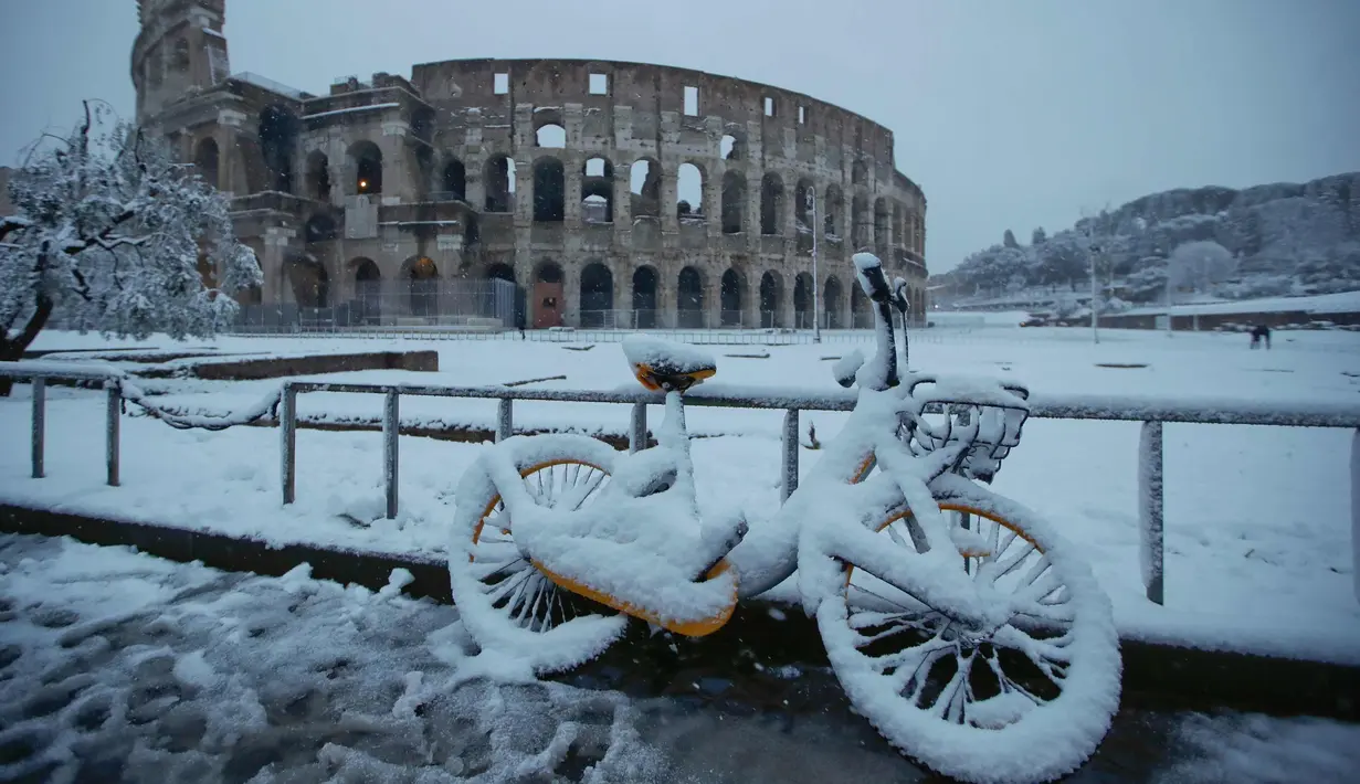 Sebuah sepeda tertutup salju tebal saat di parkir di depan Colosseum kuno di Roma, Italia (26/2). Hujan salju ini merupakan yang terlebat sejak 6 tahun terakhir. (AP Photo / Alessandra Tarantino)