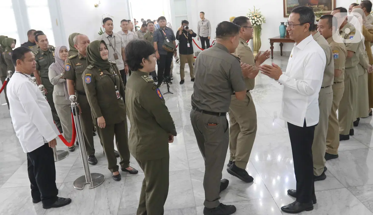 Heru mengenakan baju kemeja putih lengan panjang dengan bawahan celana hitam. Dia nampak menyalami para ASN satu-persatu. (Liputan6.com/Herman Zakharia)
