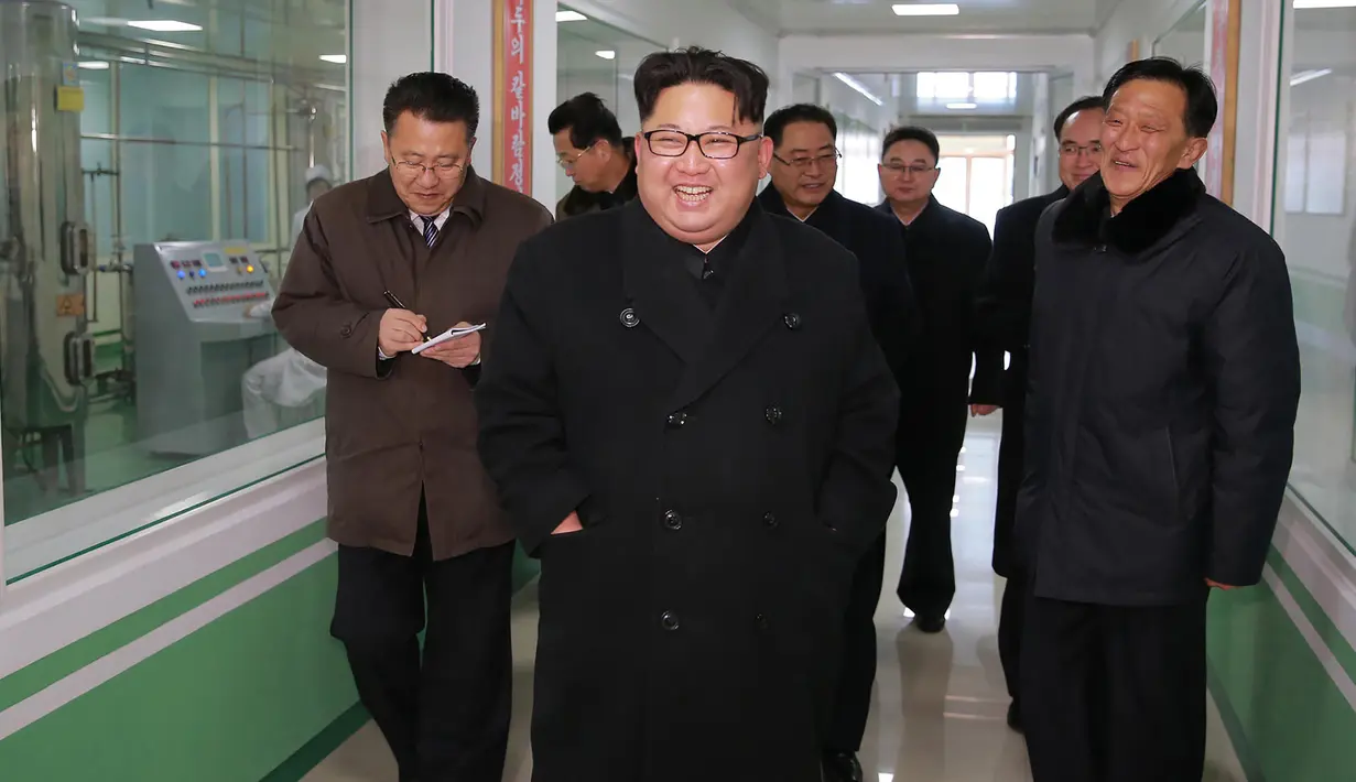 Gambar yang dirilis Kamis (25/1), memperlihatkan pemimpin Korea Utara, Kim Jong-un tersenyum sambil berjalan keliling pabrik farmasi di Pyongyang. Obat-obatan menjadi salah satu komoditi yang dijual Korut guna mendanai proyek nuklir. (KCNA VIA KNS/AFP)