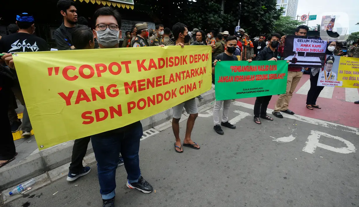 Relawan membentang poster saat pasukan Satpol PP yang hendak mengosongkan bangunan SDN Pondok Cina 1, Depok, Jawa Barat, Minggu (11/12/2022). Sebagaimana diketahui, lahan SDN Pondok Cina 1 sendiri akan dialih fungsikan oleh Pemerintah kota Depok untuk dijadikan Masjid Raya. (merdeka.com/Arie Basuki)