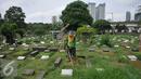 Pekerja membersihkan area makam di TPU Karet Bivak, Jakarta (2/2). Dinas Pertamanan dan Pemakaman telah menerapkan sistem online dalam pelayanan pemakaman di 77 TPU Jakarta. (Liputan6.com/Gempur M Surya)