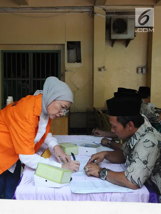 Terdakwa kasus penyebaran berita bohong atau hoaks, Ratna Sarumpaet mengisi daftar hadir di TPS 15 rutan Polda Metro Jaya, Rabu (17/4). Ratna Sarumpaet tiba mengenakan baju tahanan berwarna oranya bersama 538 tahanan menggunakan hak suaranya pada Pemilu 2019. (Liputan6.com/Herman Zakharia)