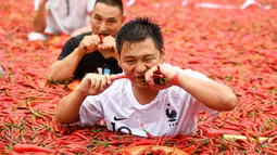 Kontestan memakan cabai saat mengambil bagian dalam kompetisi makan cabai di Ningxiang di provinsi Hunan tengah, China (8/7). Pemenang dalam kontes ini telah memakan 5 cabai dalam waktu satu menit. (AFP Photo)