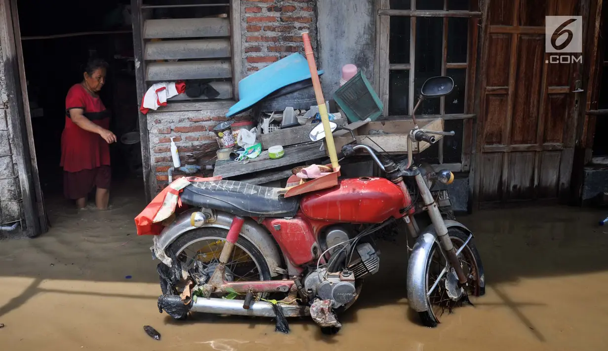 Warga berada di rumahnya yang tergenang banjir di kawasan Sawah besar Semarang, Jawa Tengah, Sabtu (8/12). Ratusan rumah tergenang banjir akibat Tanggul Sungai Banjir Kanal Timur jebol. (Liputan6.com/Gholib)