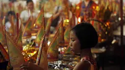 Hungry Ghost merupakan kepercayaan saat gerbang neraka terbuka untuk membiarkan roh-roh yang berkeliaran di negeri orang hidup mencari makanan. Seorang anak menghiasi persembahan di festival Hungry Ghost, Kuala Lumpur, (3/8/2014). (REUTERS/Olivia Harris)