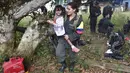 Seorang gerilyawati FARC menggendong seorang anak di kamp Magdalena Medio, Kolombia (15/3/2016). Gerilyawati FARC dikenal lebih sadis terhadap musuh daripada pasukan gerilyawan. (AFP Photo/Luis Acosta)