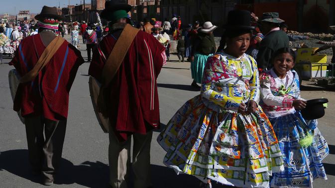 Gadis-gadis mengenakan kostum yang terbuat dari kantong plastik susu saat memeriahkan di Bolivia, Selasa (14/8). Siswa sekolah San Roque membuat kostum dari bahan daur ulang untuk meningkatkan kesadaran pengelolaan limbah padat. (AP/Juan Karita)