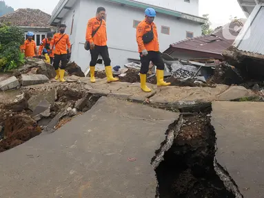 Petugas melintas di jalan yang rusak  pascagempa bumi magnitudo 5,6 di Kampung Cisarua, Desa Sarampad, Kabupaten Cianjur, Jawa Barat, Rabu (23/11/2022). Berdasarkan data BNPB sebanyak 58.362 warga mengungsi akibat gempa bumi di Kabupaten Cianjur tersebut. (merdeka.com/Arie Basuki)