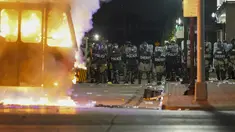 Polisi berdiri dekat truk sampah yang terbakar saat protes di Kenosha, Wisconsin, Amerika Serikat, Senin (24/8/2020). Protes dipicu oleh penembakan Jacob Blake oleh petugas polisi Kenosha sehari sebelumnya. (AP Photo/Morry Gash)