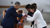 Presiden Olimpiade Tokyo 2020, Yoshiro Mori, menerima api Olimpiade saat tiba dari Yunani di Pangkalan Udara Matsushima, Jepang, Jumat (20/3). Di tengah pandemi virus corona Covid-19, prosesi menuju Olimpiade Tokyo 2020. (AFP/Philip Fong)