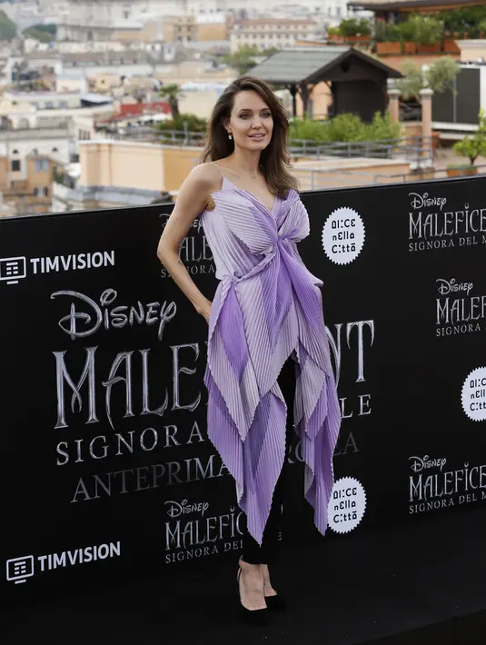 Aktris Angelina Jolie berpose saat sesi pemotretan untuk pemutaran perdana film Disney "Maleficent: Mistress of Evil" di Roma, Italia (7/10/2019). Angelina Jolie tampil cantik mengenakan gaun ungu dengan celana dan sepatu hitam. (AP Photo/Domenico Stinellis)
