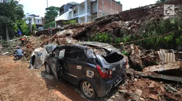 Sebuah mobil rusak setelah tertimpa material longsor tembok perumahan Lereng Indah di Perumahan Lereng Bukit Indah, Pondok Cabe Udik, Pamulang,Tangerang Selatan, Senin (8/4). Dua mobil warga perumahan Lereng Indah rusak tertimpa longsor saat hujan deras. (merdeka.com/Arie Basuki)