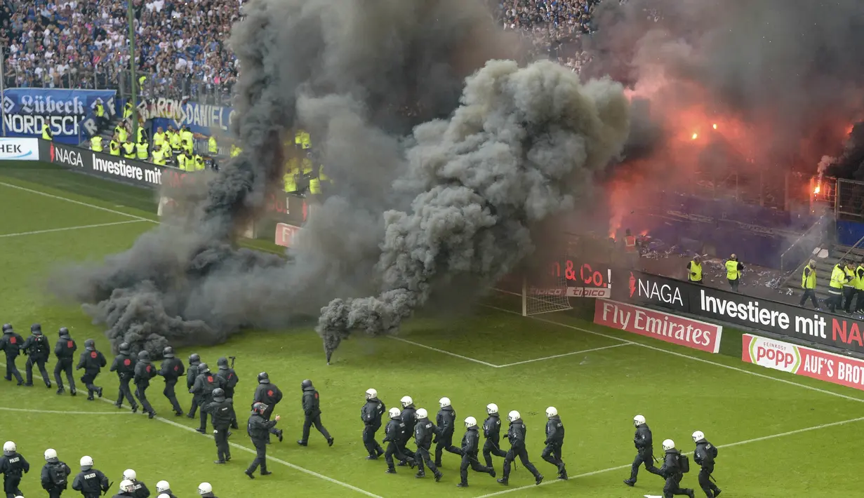 Petugas kepolisian berusaha menenangkan suporter yang mengamuk saat pertandingan antara Hamburg SV melawan VfL Borussia Moenchengladbach di Volksparkstadion, Sabtu (12/5/2018). Hamburg SV terdegradasi dari Bundesliga Jerman. (AP/Michael Sohn)