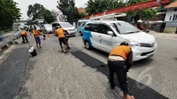Petugas mengaspal jalanan yang berlubang di Jalan Kramat Raya, Jakarta, Rabu (25/2/2015). Perbaikan dilakukan karena jalan bergelombang dan berlubang setelah terendam banjir beberapa waktu lalu. (Liputan6.com/Faizal Fanani)