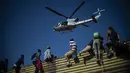 Sebuah helikopter terlihat saat para imigran memanjat pagar perbatasan antara Meksiko dan AS di Tijuana, Meksiko (25/11). Ratusan migran berusaha menyerbu pagar perbatasan yang memisahkan Meksiko dari AS. (AFP Photo/Pedro Pardo)