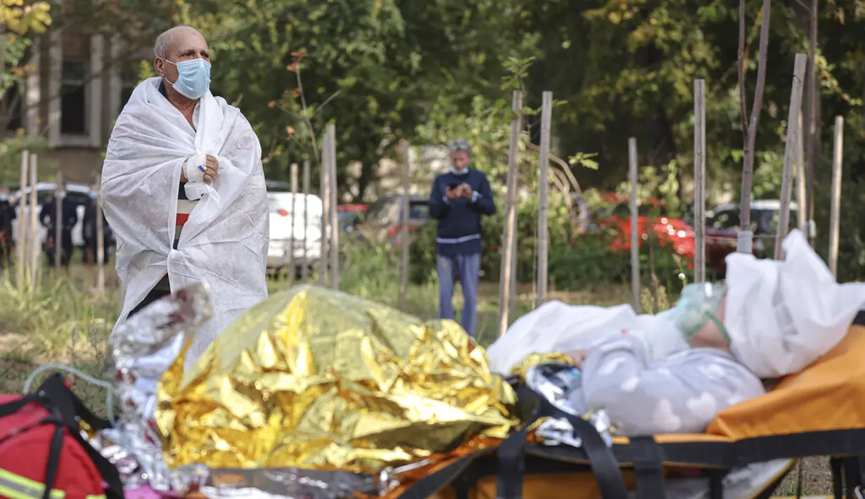 Seorang pasien yang bernapas melalui masker oksigen dievakuasi setelah kebakaran di bagian ICU COVID-19 Rumah Sakit untuk Penyakit Menular di pelabuhan Laut Hitam Constanta, Rumania (1/10/2021). Semua pasien telah dievakuasi setelah kebakaran tersebut. (AP Photo/Costin Dinca)