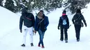 Dua imigran dari Pantai Gading berjalan menuju Colle della Scala (Col de l'Echelle) sebuah jalan yang tertutup salju, untuk melintasi perbatasan antara Italia dan Prancis di Pegunungan Alpen, Italia (13/1). (AFP/Piero Cruciatti)