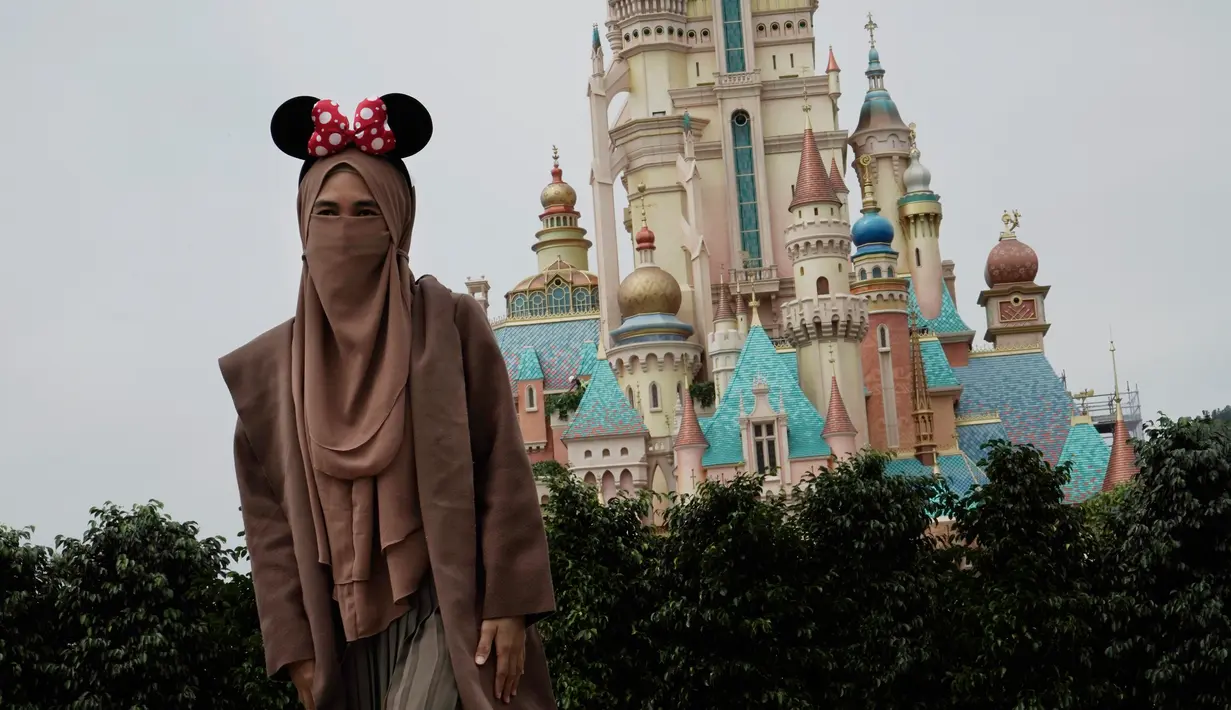 Seorang pengunjung yang mengenakan masker berpose untuk foto di Disneyland Hong Kong pada Jumat (25/9/2020). Setelah dibuka dan tutup kembali, Disneyland Hong Kong dibuka kembali untuk wisatawan. (AP Photo/Kin Cheung)