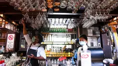 Bartender Gagan (kiri) dan seorang pelayan membersihkan bar jelang pembukaan kembali di New Delhi, 8 September 2020. Setelah sebelumnya ditutup karena pandemi COVID-19, mulai 9 September 2020 New Delhi mengizinkan bar kembali buka dengan kapasitas tempat duduk 50 persen. (Prakash SINGH/AFP)