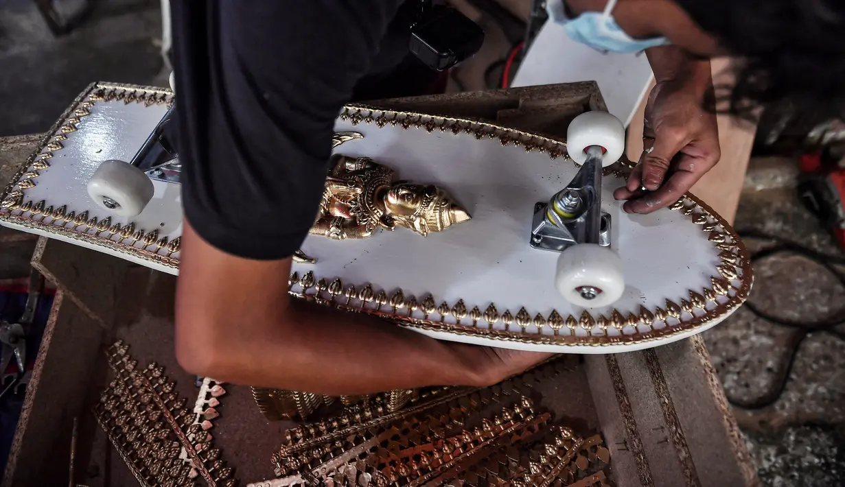 Pekerja toko peti mati Burapha memasang roda skateboard, terbuat dari kayu yang digunakan untuk peti mati, di Bangkok, 19 Maret 2021. Pembuat peti mati di Thailand mengubah kayu peti mati sisa menjadi skateboard murah di tengah booming popularitas olahraga. (Lillian SUWANRUMPHA/AFP)