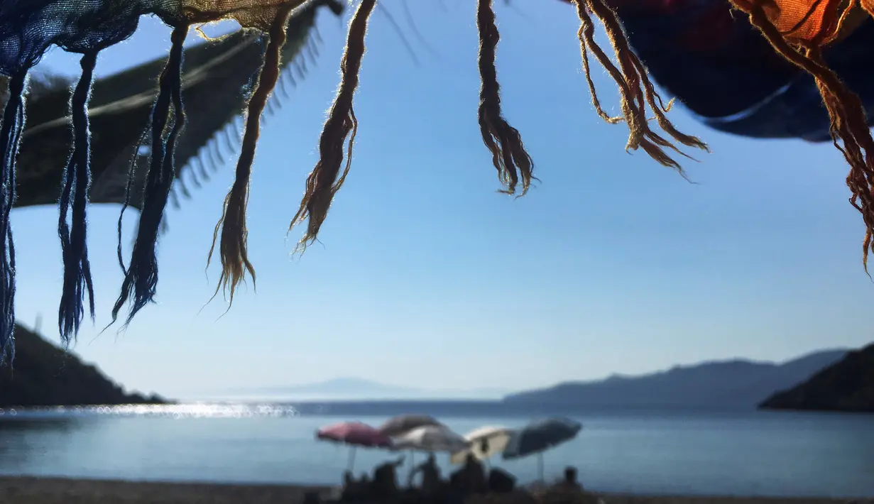 Anak-anak muda duduk di tepi pantai Semenanjung Peloponese, Kardamyli, Yunani, Minggu (28/6/2020). (AP Photo/Lefteris Pitarakis)