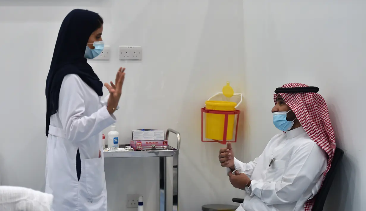 Seorang perawat berbicara kepada seorang pria sebelum memberikan vaksin Covid-19 di pusat vaksinasi yang diawasi Kementerian Kesehatan Arab Saudi di Riyadh, Arab Saudi, Kamis (17/12/2020). Berdasarkan informasi, proses vaksinasi di Arab Saudi akan dilakukan dalam tiga tahap.  (AFP/Fayez Nureldine)