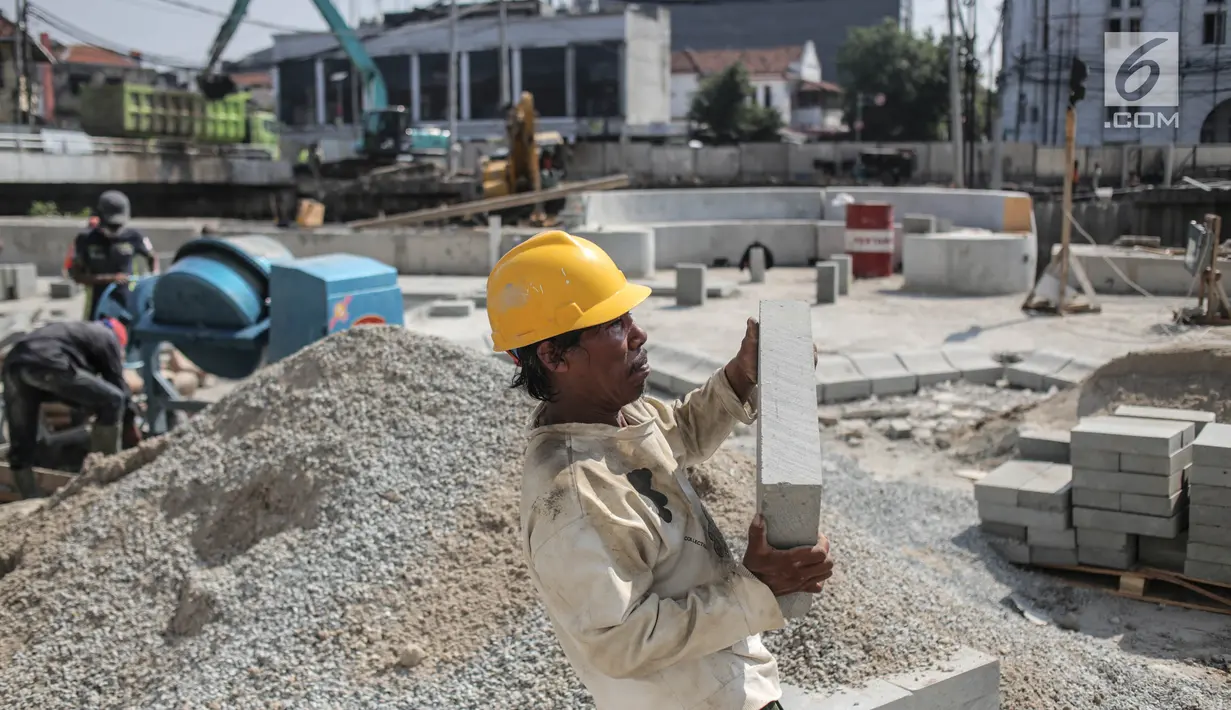 Pekerja mengangkat batu saat pengerjaan proyek revitalisasi kawasan Kota Tua di Jakarta, Jumat (15/9). Revitalisasi kawasan Kali Besar menjadi bagian dari program revitalisasi kawasan kota Tua. (Liputan6.com/Faizal Fanani)