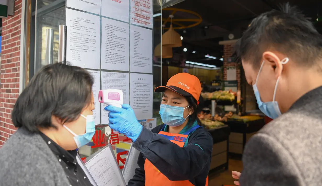 Pekerja memeriksa kode QR kesehatan dan suhu tubuh pelanggan di toko bahan makanan segar di Distrik Xiling, Kota Yichang, Provinsi Hubei, China, Jumat (20/3/2020). Warga kini dapat memasuki dan meninggalkan area tempat tinggal mereka dengan kode QR kesehatan yang memenuhi syarat. (Xinhua/Cheng Min)