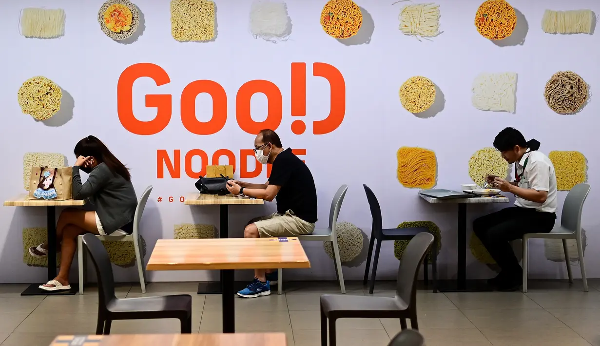 Orang-orang duduk di bawah papan yang memajang mi instan yang berbeda di sebuah foodcourt di Bangkok (25/8/2022). Thailand akan menaikkan harga mie instan Thailand, kata departemen perdagangan 24 Agustus menandai kenaikan harga pertama pada kebutuhan pokok harian dalam 14 tahun. (AFP/Vatsyayana)