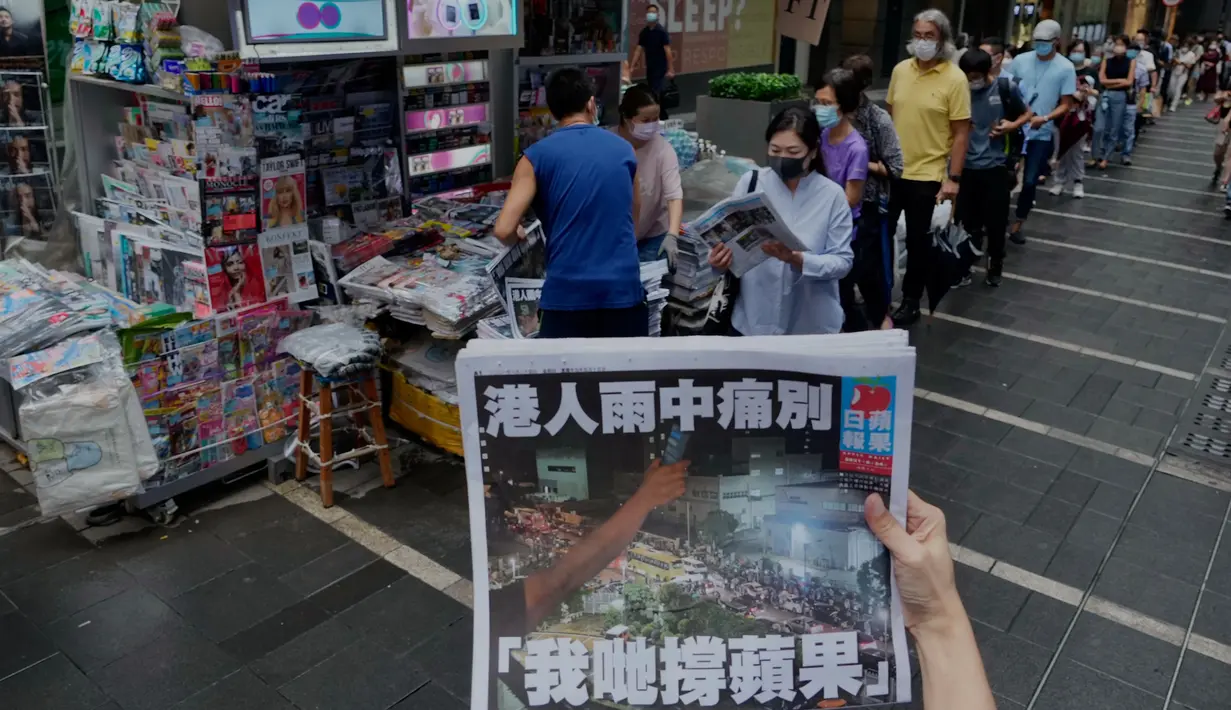 Seorang wanita mencoba mengambil gambar edisi terakhir Apple Daily di depan stan surat kabar di mana orang-orang antre untuk membeli koran di sebuah jalan pusat kota di Hong Kong, Kamis (24/6/2021) Apple Daily mencetak edisi terakhir, Kamis (24/6), setelah 26 tahun beroperasi. (AP Photo/Vincent Yu)