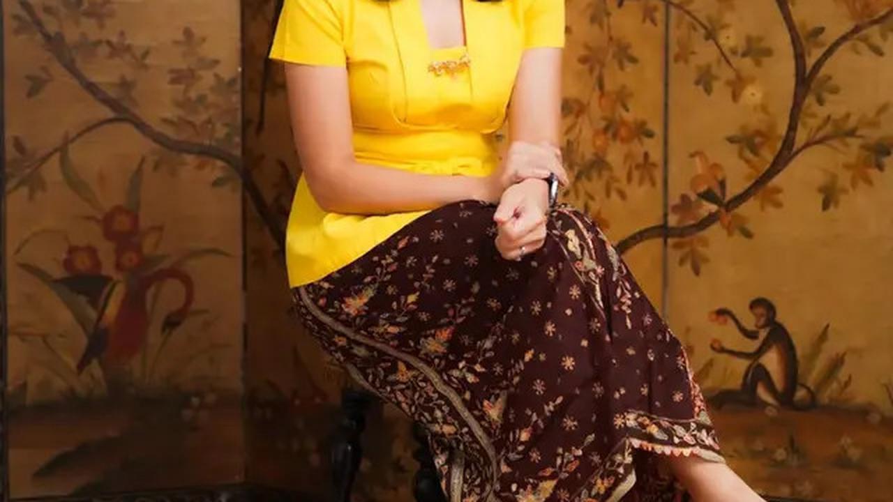 Dian Sastro memikat dengan kebaya kuning cerah dan kain batik merah bata yang cocok.