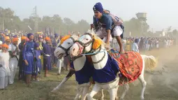 Atraksi berkuda dari anggota militer tradisional Sikh saat perayaan Fateh Divas di Amritsar (20/10). Para anggota militer ini menujukan aksi berkuda mereka untuk meramaikan perayaan Fateh Divas. (AFP/Narinder Nanu)