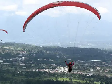 Seorang paraglider lepas landas dari lereng bukit di Puncak, Bogor, Jawa Barat, Kamis (2/12/2021). Destinasi wisata alam Bukit Paralayang Puncak Bogor sangat cocok untuk dikunjungi pada liburan akhir pekan bersama keluarga, sahabat maupun pasangan tercinta. (Goh Chai Hin/AFP)