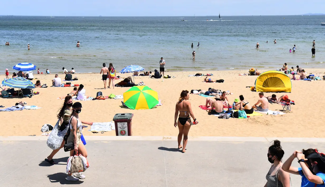 Wisatawan berjemur saat menikmati cuaca hangat di Pantai St Kilda Melbourne, Australia, Selasa (3/11/2020). Negara bagian Victoria di Australia mencatat nol kasus penularan COVID-19 selama empat hari berturut-turut setelah berjuang melawan gelombang kedua wabah pandemi. (AFP/William West)