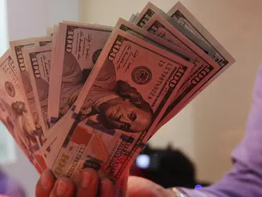 Petugas menunjukkan uang pecahan US$100 di penukaran uang, Jakarta, Rabu (23/9/2015). Mata uang Rupiah  sempat melemah ke level 14.655 per dolar AS pada perdagangan pukul 09.50 waktu Jakarta. (Liputan6.com/Angga Yuniar)