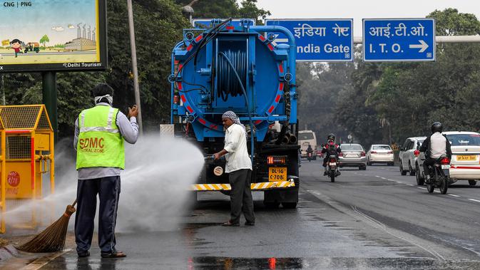 Petugas menyemprotkan air ke pohon-pohon untuk mengurangi polusi udara di pinggir jalan New Delhi, Rabu (6/11/2019). Tingkat polusi udara di Ibu Kota India itu kian memburuk, hingga mengancam kesehatan masyarakat. (Photo by Prakash SINGH / AFP)