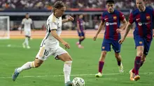 Gelandang Real Madrid Luka Modric (10) menggiring bola melawan gelandang FC Barcelona Frenkie de Jong (kanan) dan bek Andreas Christensen dalam laga pramusim bertajuk Soccer Champions Tour di AT&T Stadium, Texas, Amerika Serikat, Minggu (30/7/2023) dini hari WIB. (AP Photo/Jeffrey McWhorter)