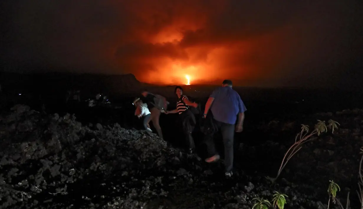 Warga berjalan kaki menaiki lereng untuk melihat guguran lava pijar yang keluar dari gunung api Piton de la Fournaise atau Peak of the Furnace di Pulau Reunion, Samudera Hindia, Prancis, Selasa (13/8/2019). Letusan Piton de la Fournaise berlanjut hingga hari ketiga. (Richard BOUHET/AFP)