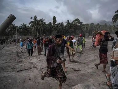 Warga menyelamatkan barang-barang mereka di daerah yang tertutup abu vulkanik setelah letusan gunung Semeru di desa Sumber Wuluh di Lumajang, Jawa Timur, Minggu (5/12/2021). BNPB menyatakan, korban meninggal akibat Gunung Semeru meletus mencapai 13 orang. (AFP /Juni Kriswanto)