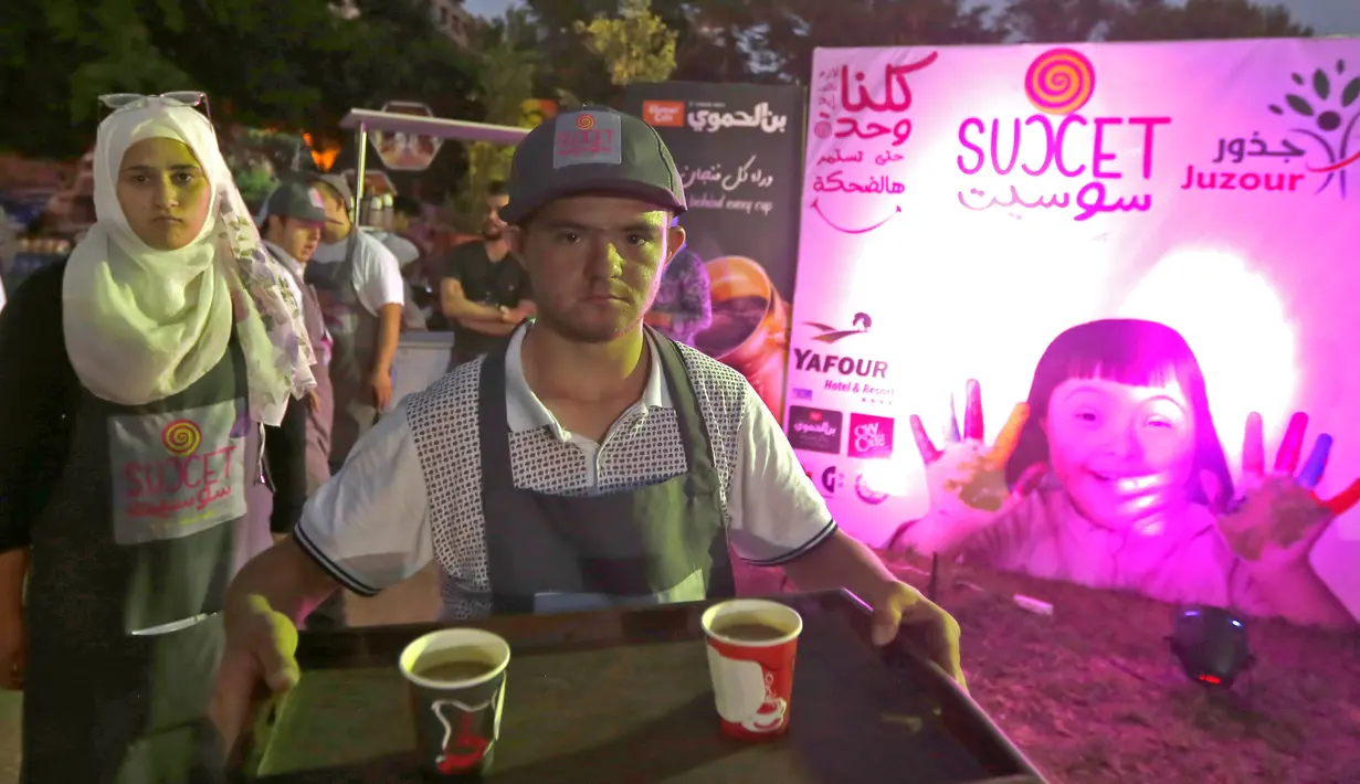 Seorang anak down syndrome Abdel Rahman membawa minuman di kedai kopi Sucet  selama festival "Sham gather us" di Damascus (11/7). Enam belas anak laki-laki dan perempuan down syndrome bekerja di Cafe Sucet melayani pelanggan. (AFP Photo/Louai Beshara)