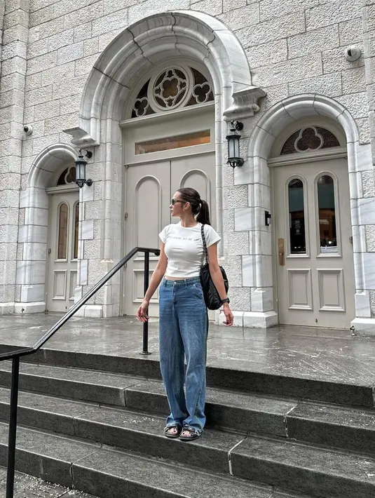 Enzy Storia tampil chic dengan atasan kaus putih, dipadu dengan celana jeans. Penampilan kasualnya ini semakin manis dengan gaya rambut ponytail, shoulder bag, dan sunglasses. [Foto: Instagram/enzystoria]