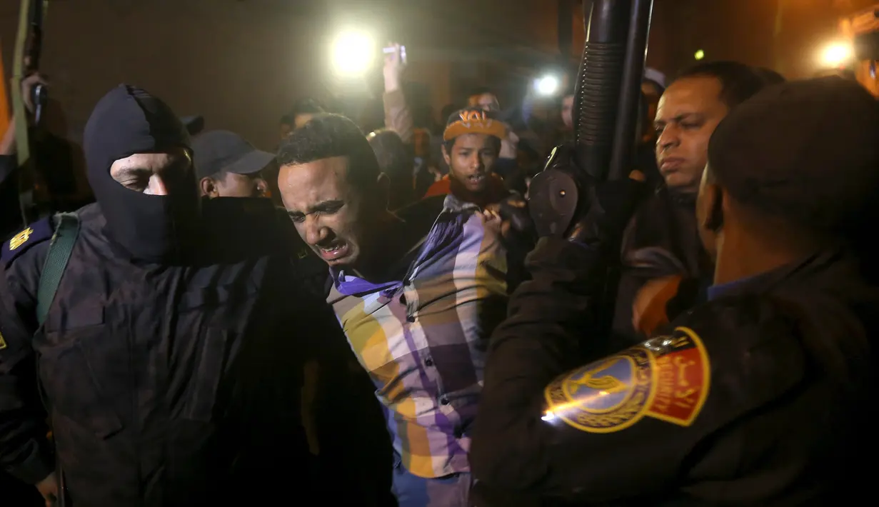 Polisi mengamankan seorang pria di lokasi ledakan yang terjadi saat penggerebekan sebuah apartemen di Kairo yang diduga menjadi tempat persembunyian militan, Mesir, Kamis (21/1). Enam orang tewas, termasuk tiga polisi. (REUTERS/Mohamed Abd El Ghany)