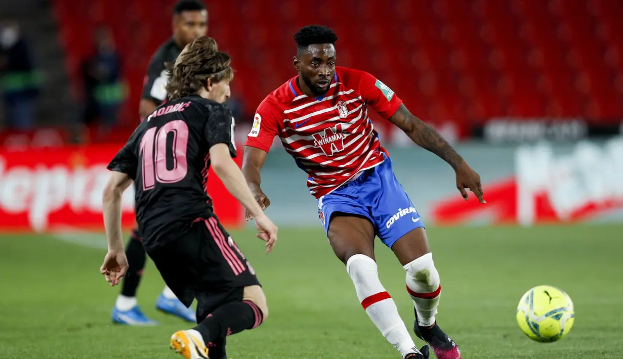 Gelandang Granada, Yan Eteki (kanan) berebut bola dengan gelandang Real Madrid, Luka Modric dalam laga lanjutan Liga Spanyol 2020/2021 pekan ke-36 di Los Carmenes Stadium, Granada, Kamis (13/5/2021). Granada kalah 1-4 dari Real Madrid. (AP/Fermin Rodriguez)