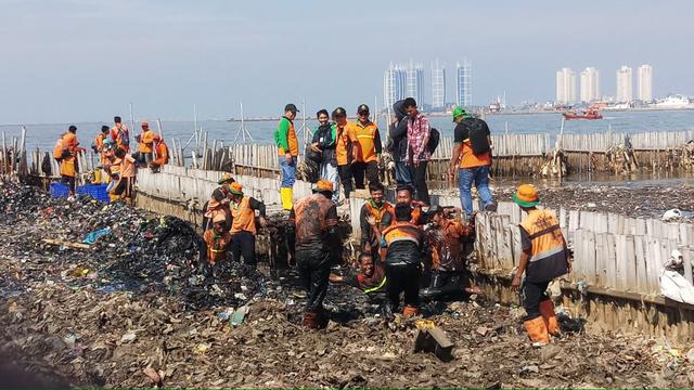 Petugas kebersihan mengangkat sampah dari Teluk Jakarta