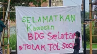 Spanduk penolakan rencana pembangunan tol Soreang-Ciwidey-Pangalengan dibentangkan saat aksi yang digelar sejumlah aktivis lingkungan dan mahasiswa di Soreang, Kabupaten Bandung, Kamis, 9 Juni 2022.